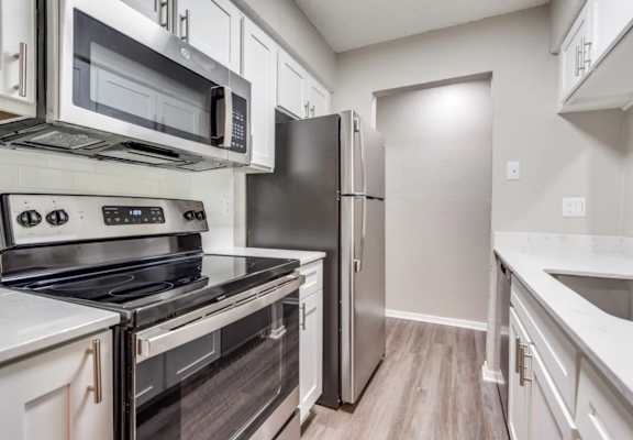 A kitchen with a stove, oven, microwave, refrigerator, and sink. at Infinity on the Oaks Apartments, Dallas, TX