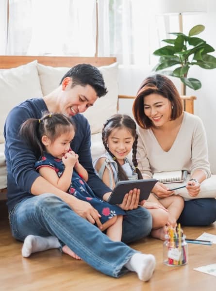 a family sitting on the floor in their living room looking at a tablet