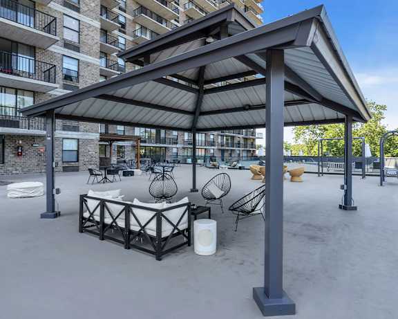 a patio with a table and chairs under an awning with a building in the background