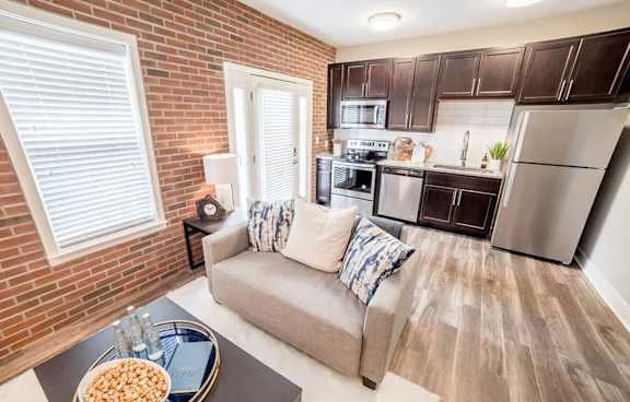 A modern kitchen with a grey couch and a wooden table at The Foundry Apartments , South Bend, IN, 46617