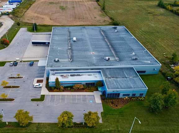 An aerial view of a large blue building with a parking lot in front.