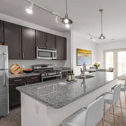 A modern kitchen with a granite countertop and stainless steel appliances.