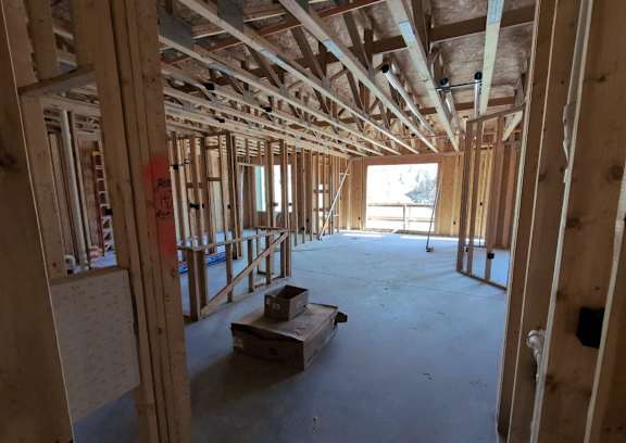 a house under construction with wood studs and a wood floor and walls