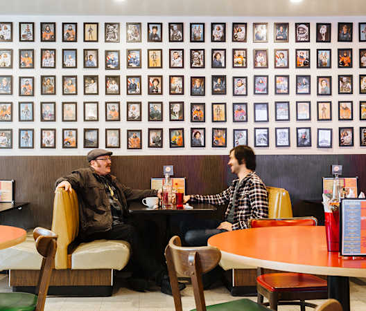 people sitting at a table in front of a wall of framed photos at The Hemlock, Seattle, WA