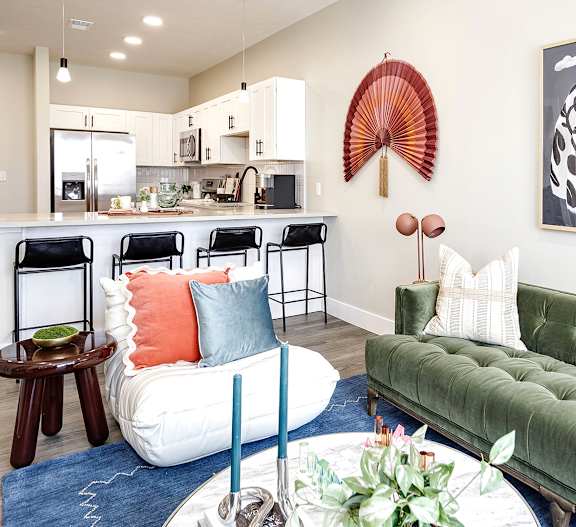 A living room with a green couch and a dining area in the background.