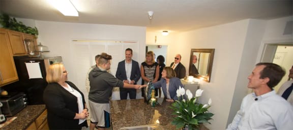 a group of people standing in a kitchen and shaking hands
