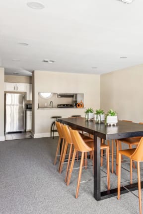 Clubhouse dining area with tall table and seats next to kitchen at Bandera Crossing apartments in San Antonio, TX