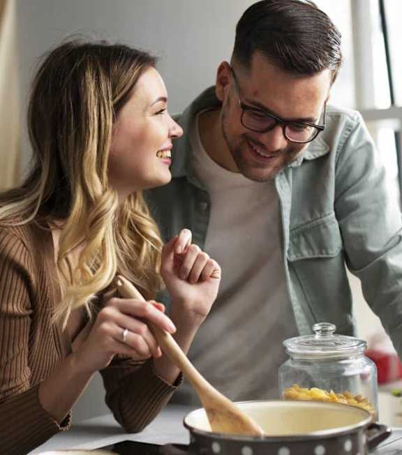 A man and a woman are cooking together in a kitchen at The Woodlands Apartments, Milton Keynes