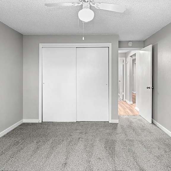 A room with a ceiling fan and a white door.