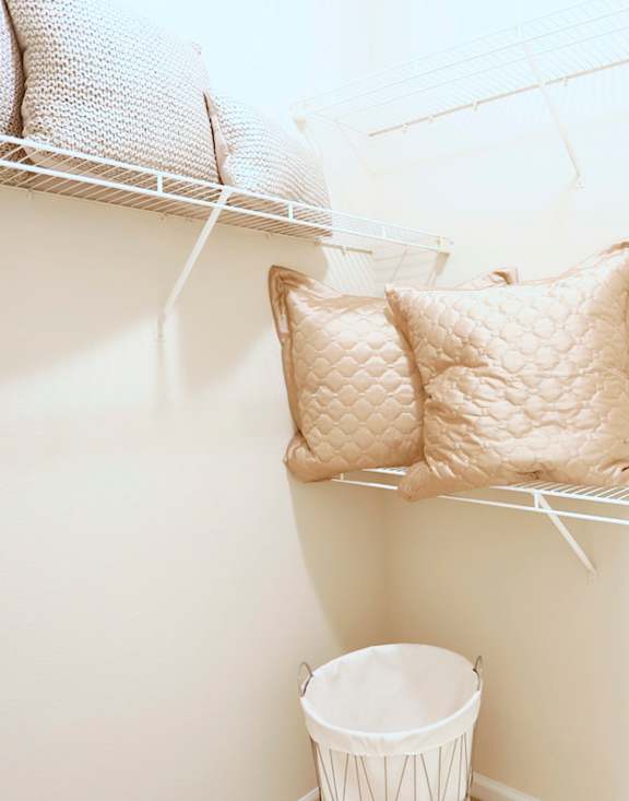 Two pillows are hanging on a white wire rack.