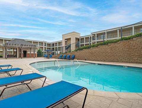 A pool area with blue lounge chairs and a brick wall at The Heights Apartments, AL 36104