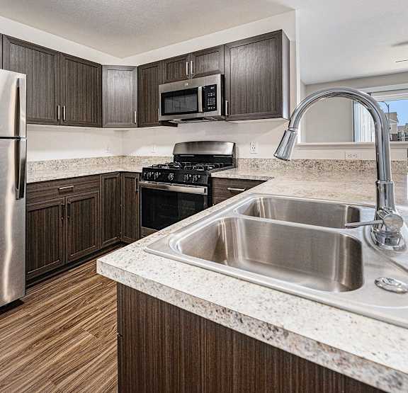 Dark Mocha Kitchen Cabinetry and Stainless Steel Appliances at Copper Creek Apartment Homes in Maize, KS