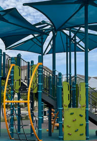 a playground with a slide and umbrella at East Meadows Apartments
