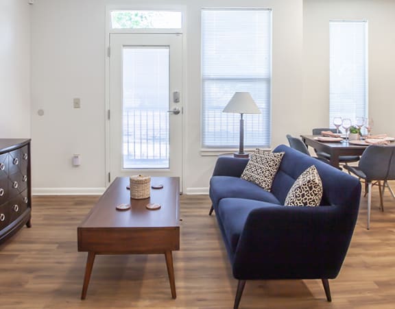 a living room with a couch and a dining table and a refrigerator surrounded by cabinets