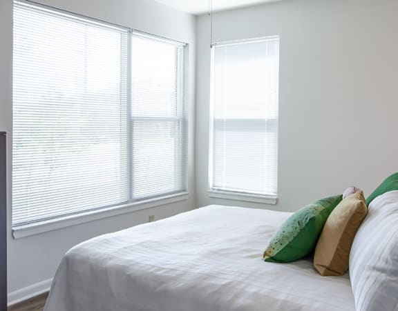 a bedroom at Beecher Terrace apartments with two windows and a bed with white sheets and pillows