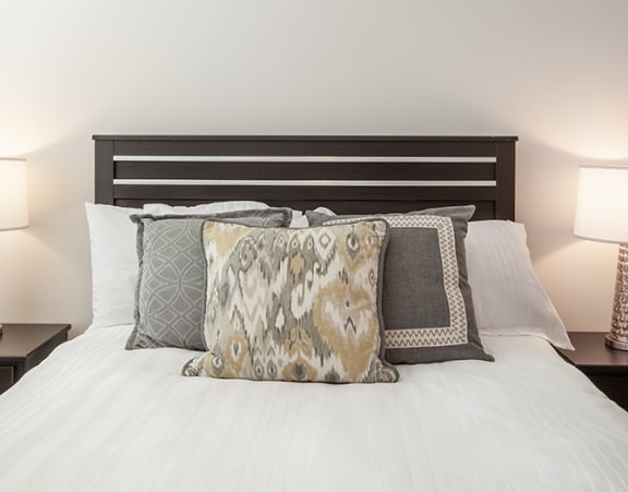 a bedroom with a bed with pillows and two lamps