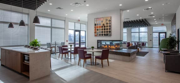 a Clubhouse lobby with a fireplace and a table with chairs with a stone kitchen island