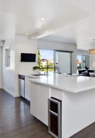 A modern kitchen with a white island and wooden floors.