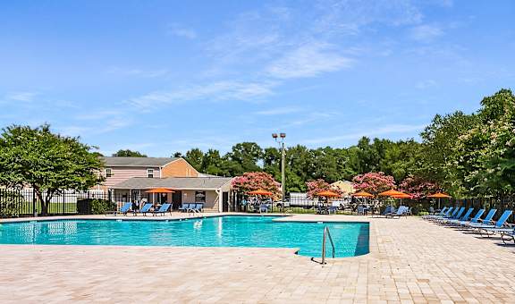 a swimming pool with blue chairs around it and a house in the background