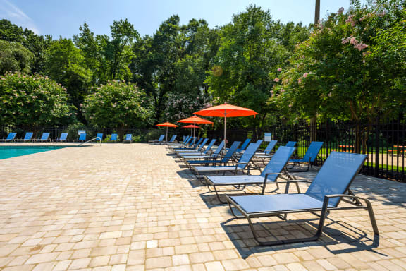 a pool with lounge chairs and umbrellas at Staples Mill Townhomes, Richmond, VA