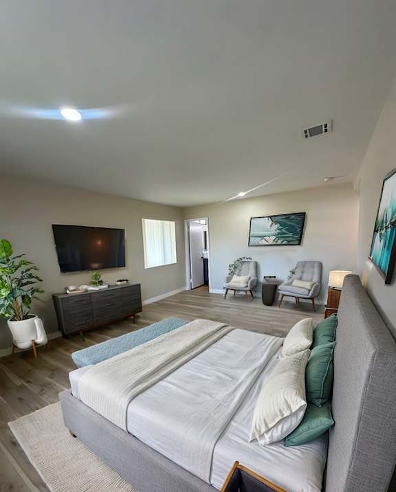 A bedroom with a large bed and a painting on the wall.