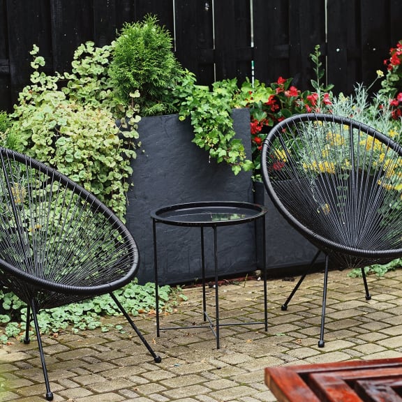 a patio with two chairs and a table on a brick patio