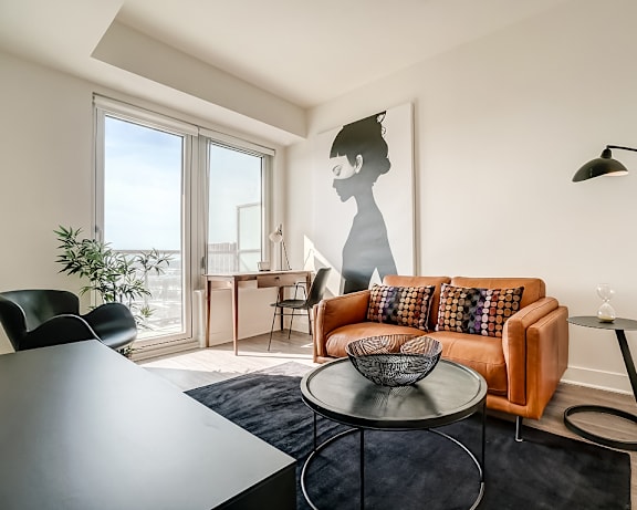 A living room with a green chair and a white sofa. at The Dale Apartments , Ottawa