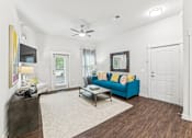 Thumbnail 21 of 31 - A living room with a blue couch and a ceiling fan.