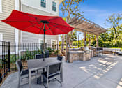 Thumbnail 13 of 31 - A red umbrella is on a patio table.