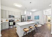 Thumbnail 23 of 31 - A kitchen with a white island and stools.