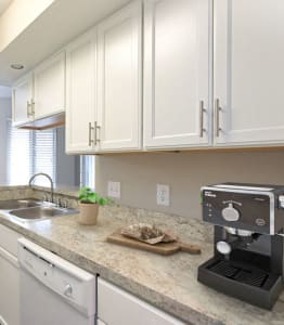 A kitchen with a sink, a coffee maker, and a dining table with chairs. at Chinoe Creek Apartments in Lexington KY