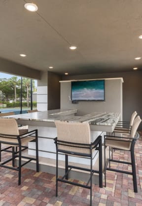 a bar area with a television and a pool in the background