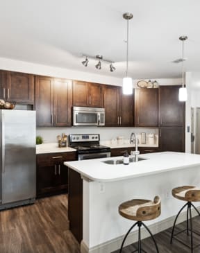 a kitchen with a large white island with three stools in front of it