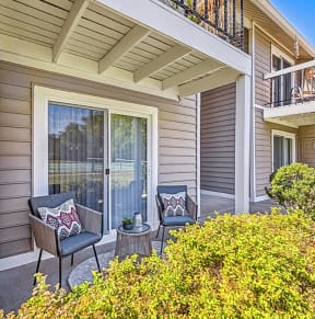 a patio with two chairs and a table in front of a house