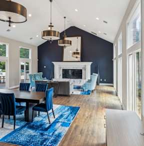 A modern dining room with a fireplace and blue chairs.
