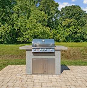 A brick patio with a built in BBQ grill.
