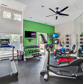 a home gym with exercise equipment and a ceiling fan