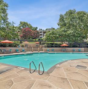 a patio with a pool and tables with umbrellas