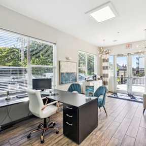 A room with a desk, chairs and a window.
