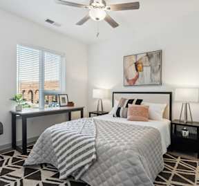 A bedroom with a large bed, a desk with a chair, and a ceiling fan.