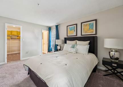 A bedroom with a large bed and a nightstand with a lamp.