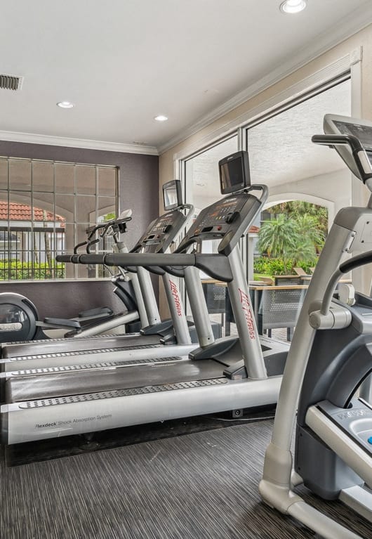 the gym is equipped with cardio equipment and window views of the pool