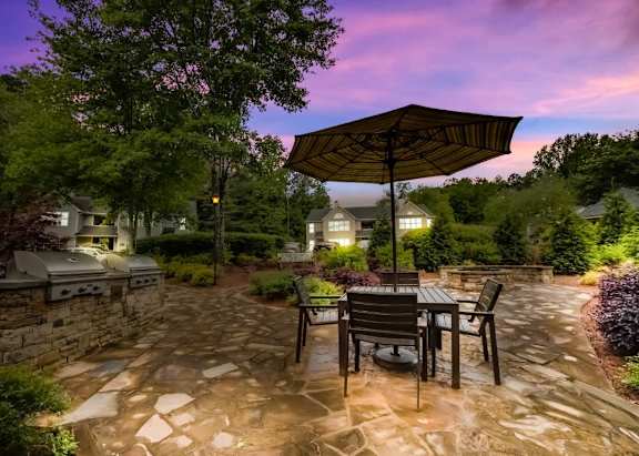 A patio with a table and chairs under an umbrella.