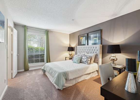 A bedroom with a large bed and a desk with a chair.