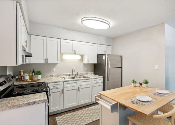 a kitchen with white cabinets and stainless steel appliances and a wooden table