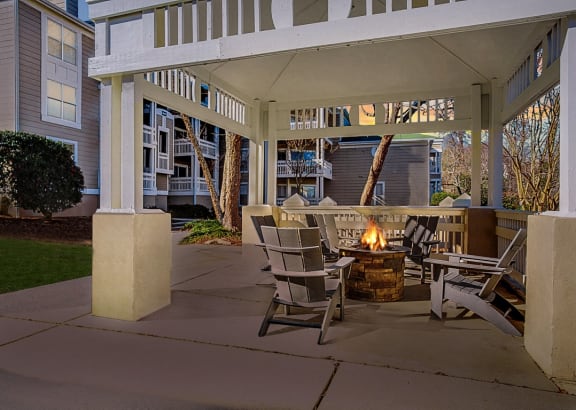 a covered patio with a fire pit and rocking chairs