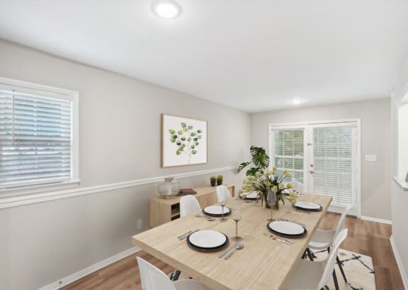 a dining room with a wooden table and chairs and two windows at Lake Johnson Mews Apartments, PRG Real Estate Management, Raleigh, 27606