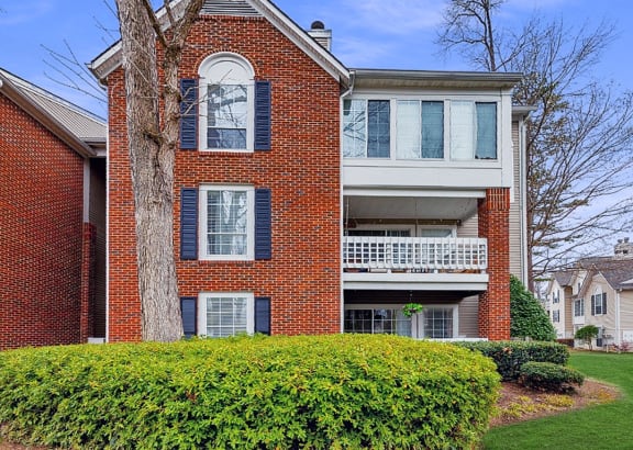 a red brick apartment building with a balcony and a yard