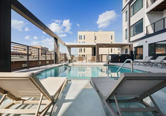 A pool surrounded by chairs and buildings at The Box, Richmond, VA, 23224