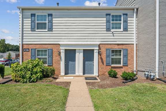 A house with a grey siding and a brick base with the number 4106 on it.